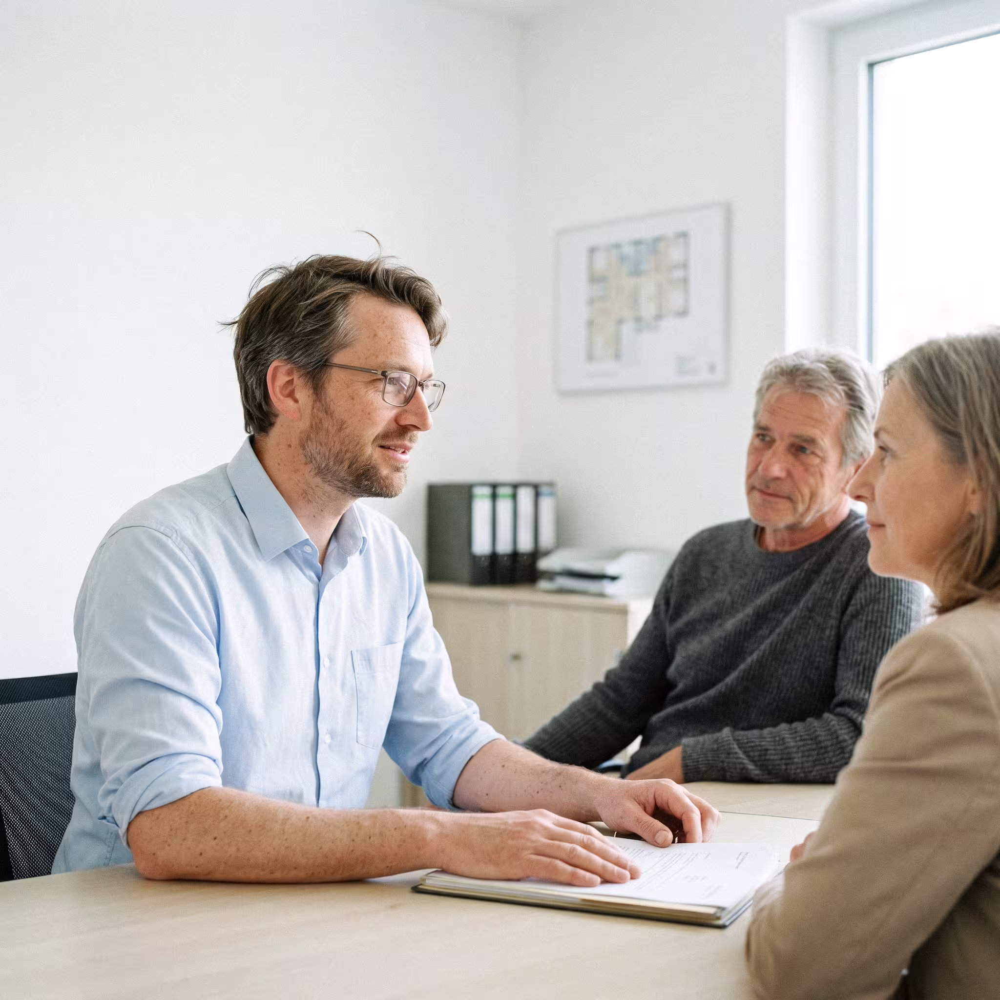 Modernes Wohnhaus in Hellgelb und Weiß mit Balkonen und begrünter Außenanlage.