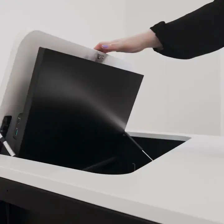 SMESK Flip: Eine Hand drückt die Klappe mit dem Monitor in die Tischplatte, danach öffnet sich die Klappe wieder.