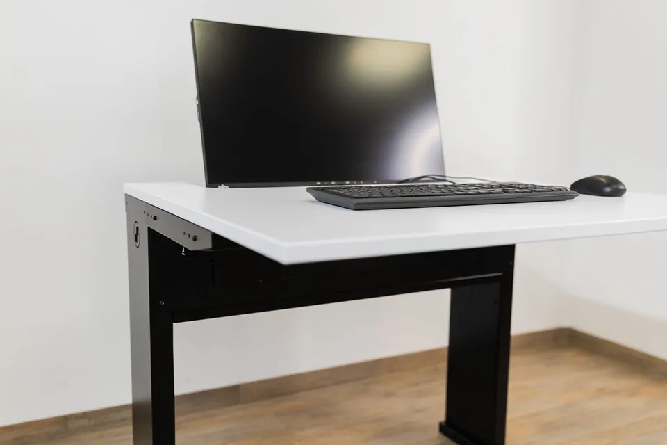 Nahaufnahme am SMESK Semi: Der Monitor ist halb in die weiße Tischplatte eingelassen, davor liegen Tastatur und Maus
