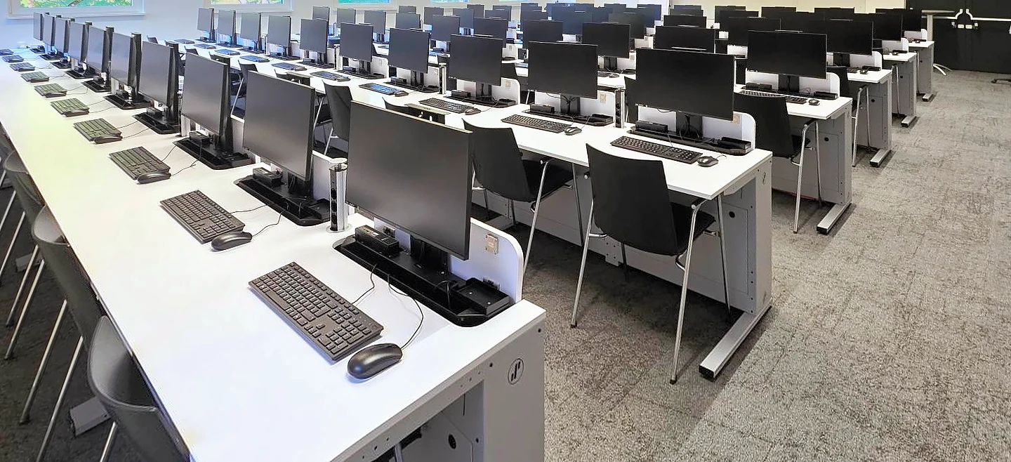 Derselbe Raum als Computerraum: an allen Plätzen sind die Monitore ausgefahren, davor liegen Tastatur und Maus