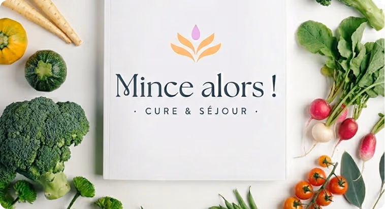 Livre ouvert intitulé 'Mince alors ! Cure & Séjour' entouré de légumes frais colorés, dont brocoli, radis, tomates cerises et courge.