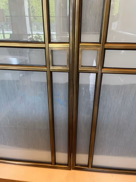 Modern double doors with frosted glass panels framed in brass-colored metal.