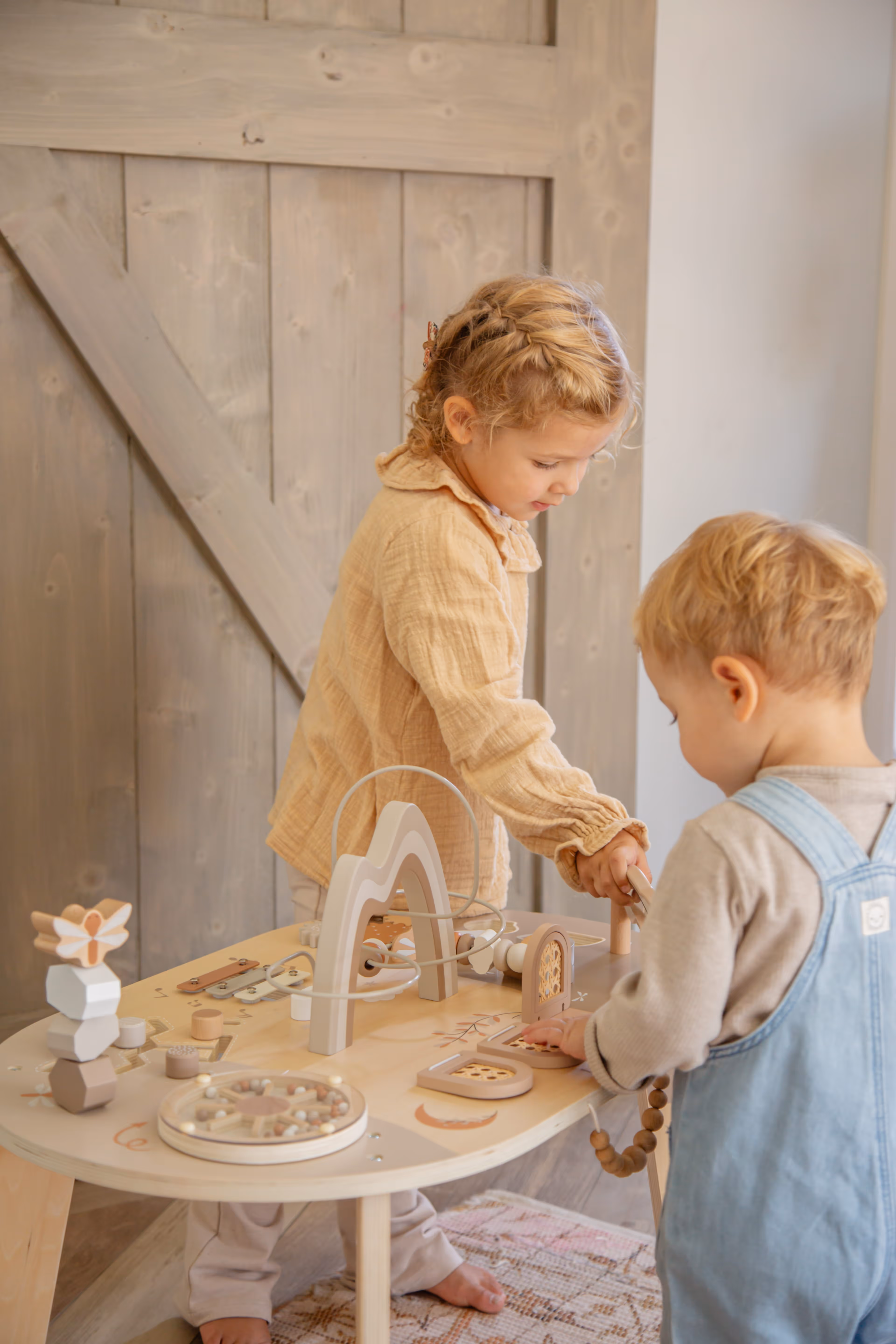Deux enfants jouant avec la roulette de la table d’activité enfant en bois avec jeux interactifs