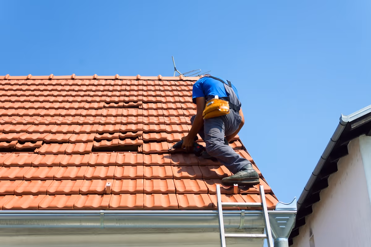 Roofer repairing damaged clay tile shingles on a residential roof