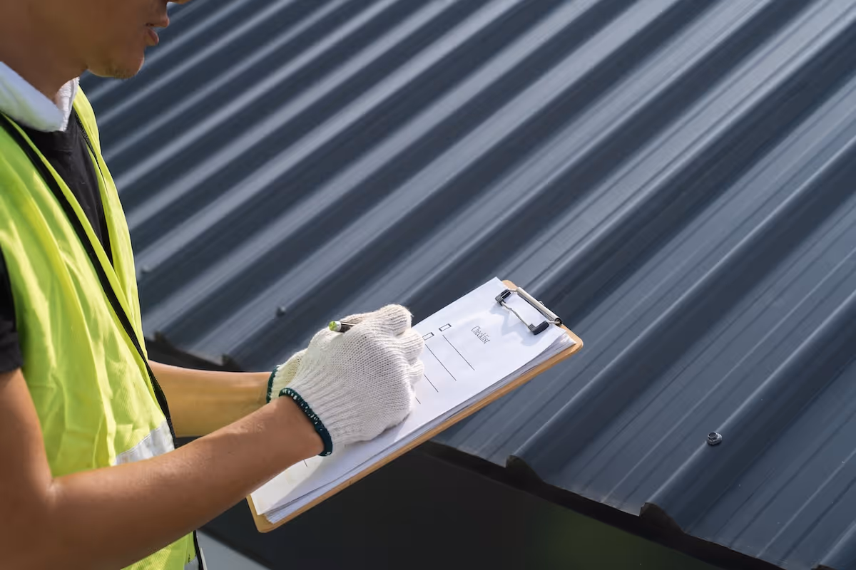 Roof inspector with clipboard reviewing a metal roof installation