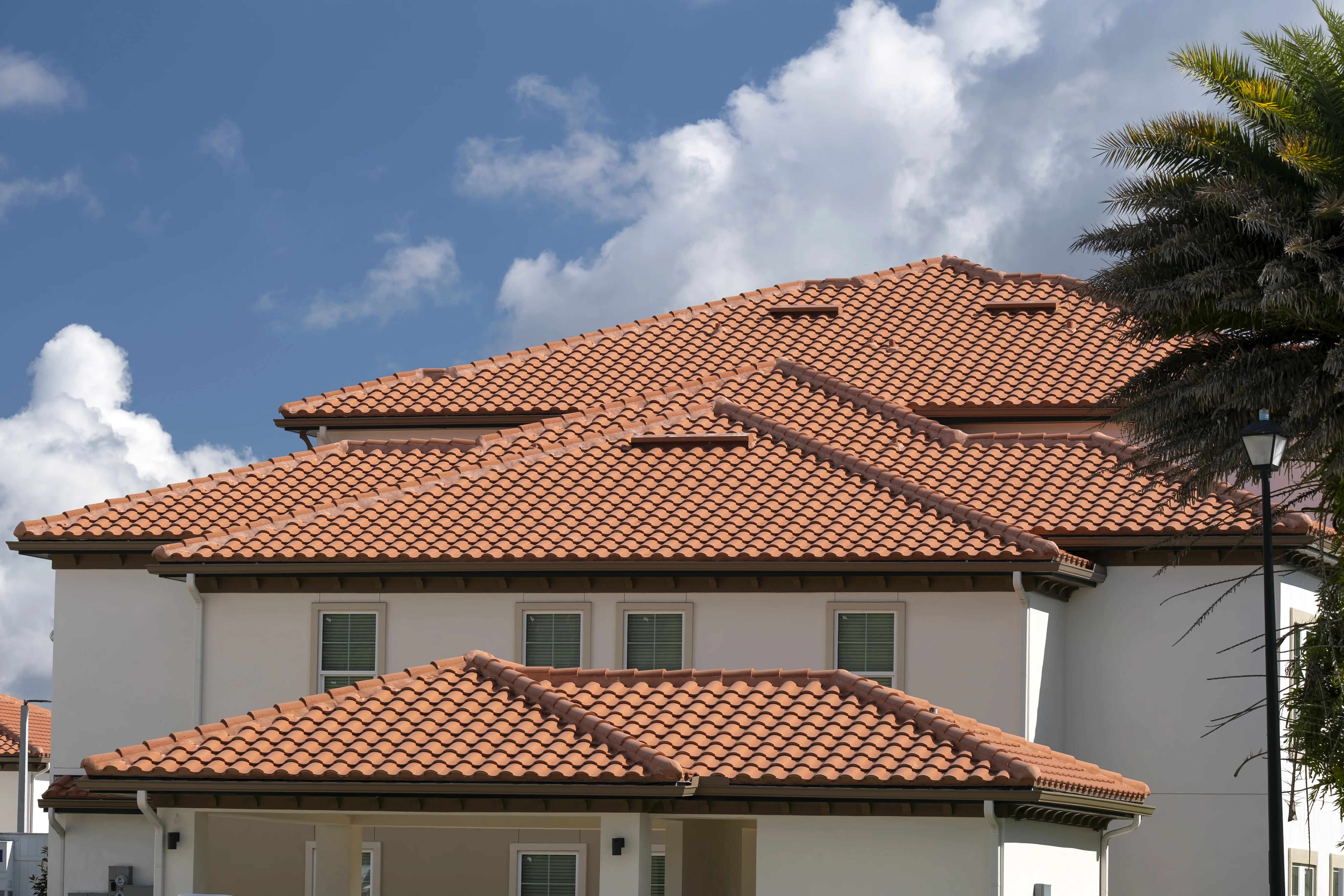 Mediterranean-style home with terracotta tile roof and palm trees