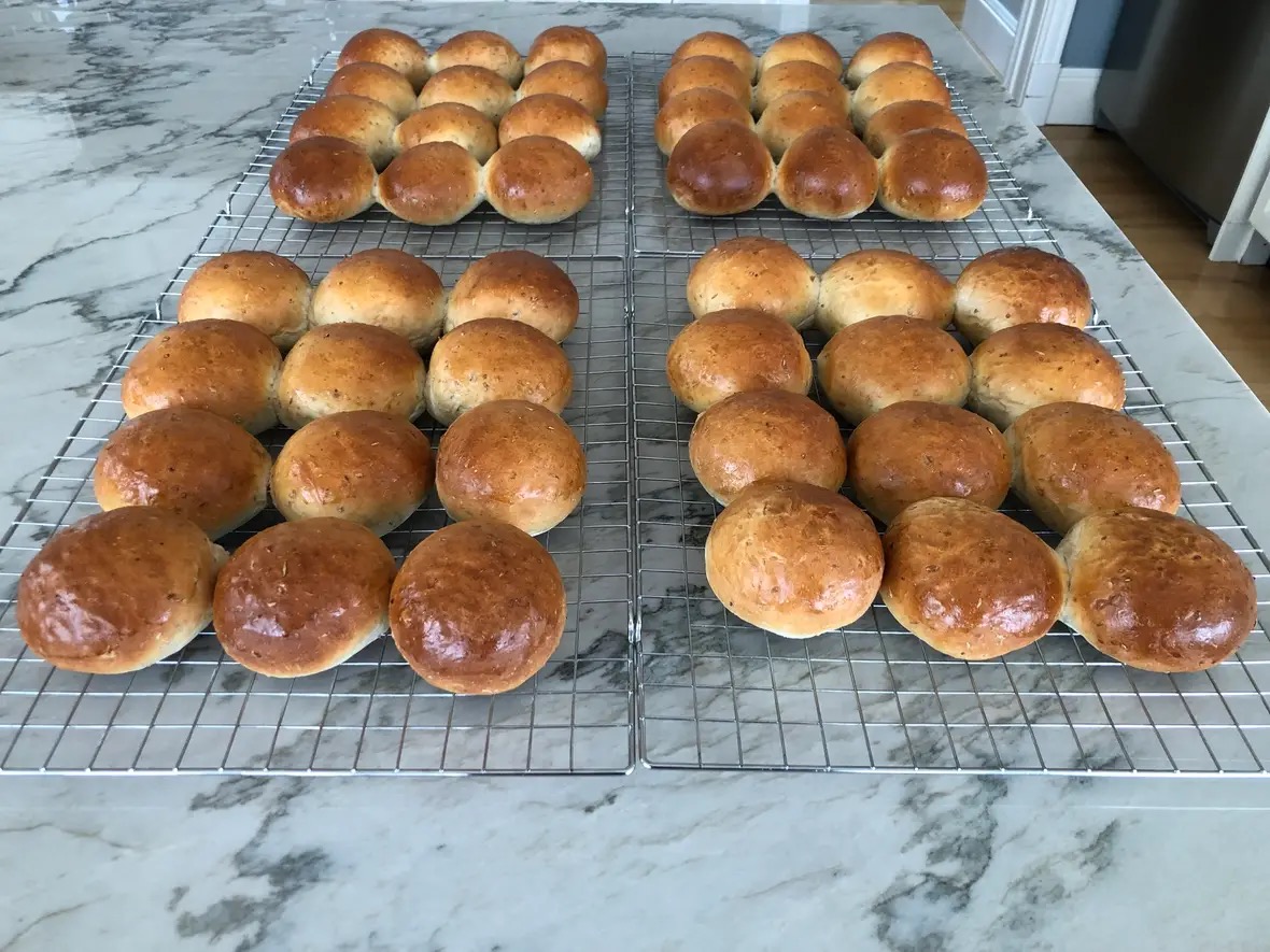 A fresh batch of Sourdough Hamburger Buns cooling on baking trays.