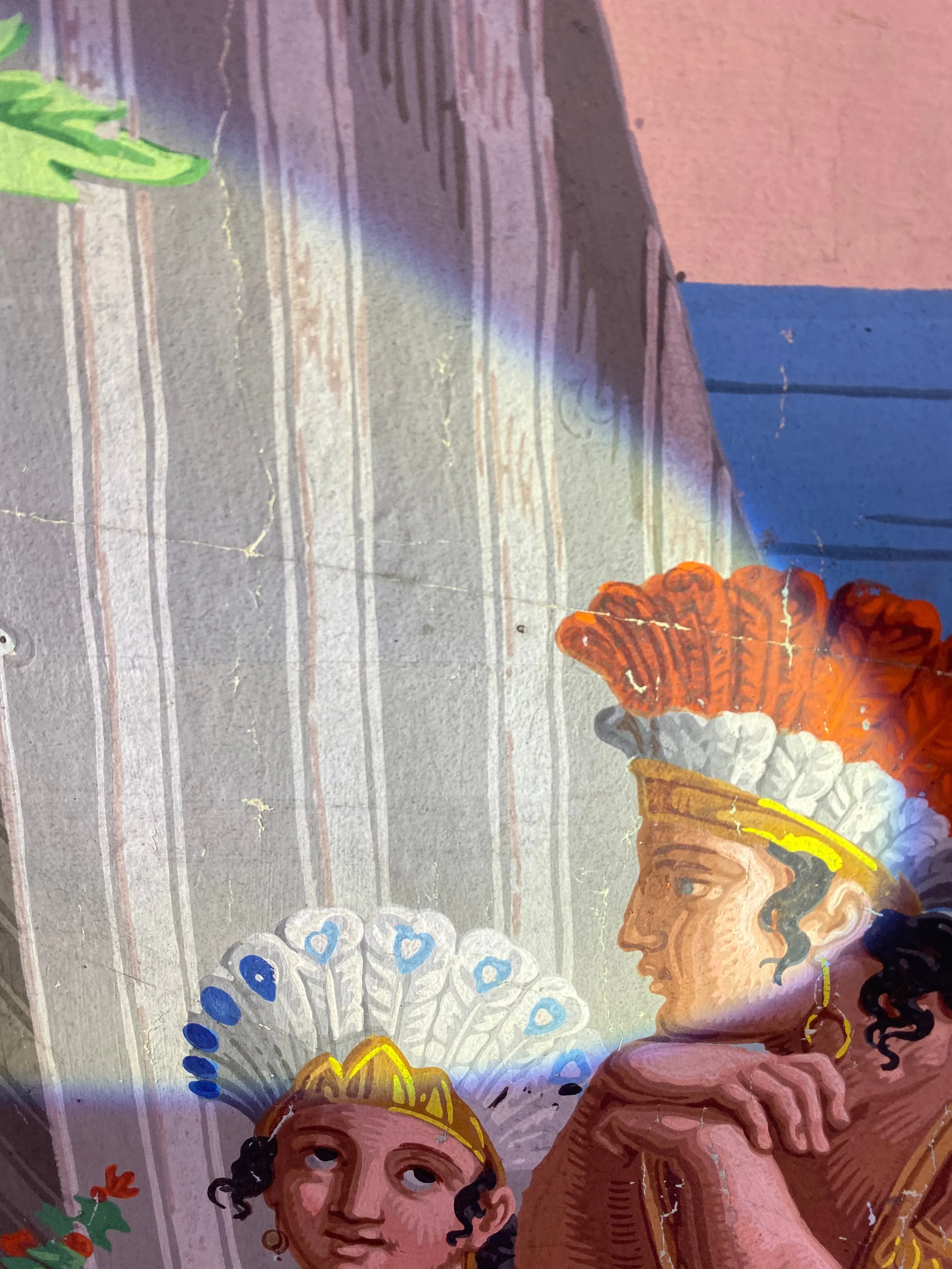 Détail d'une fresque murale représentant deux figures humaines avec des coiffes traditionnelles colorées, l'une regardant vers la droite et l'autre vers l'avant.