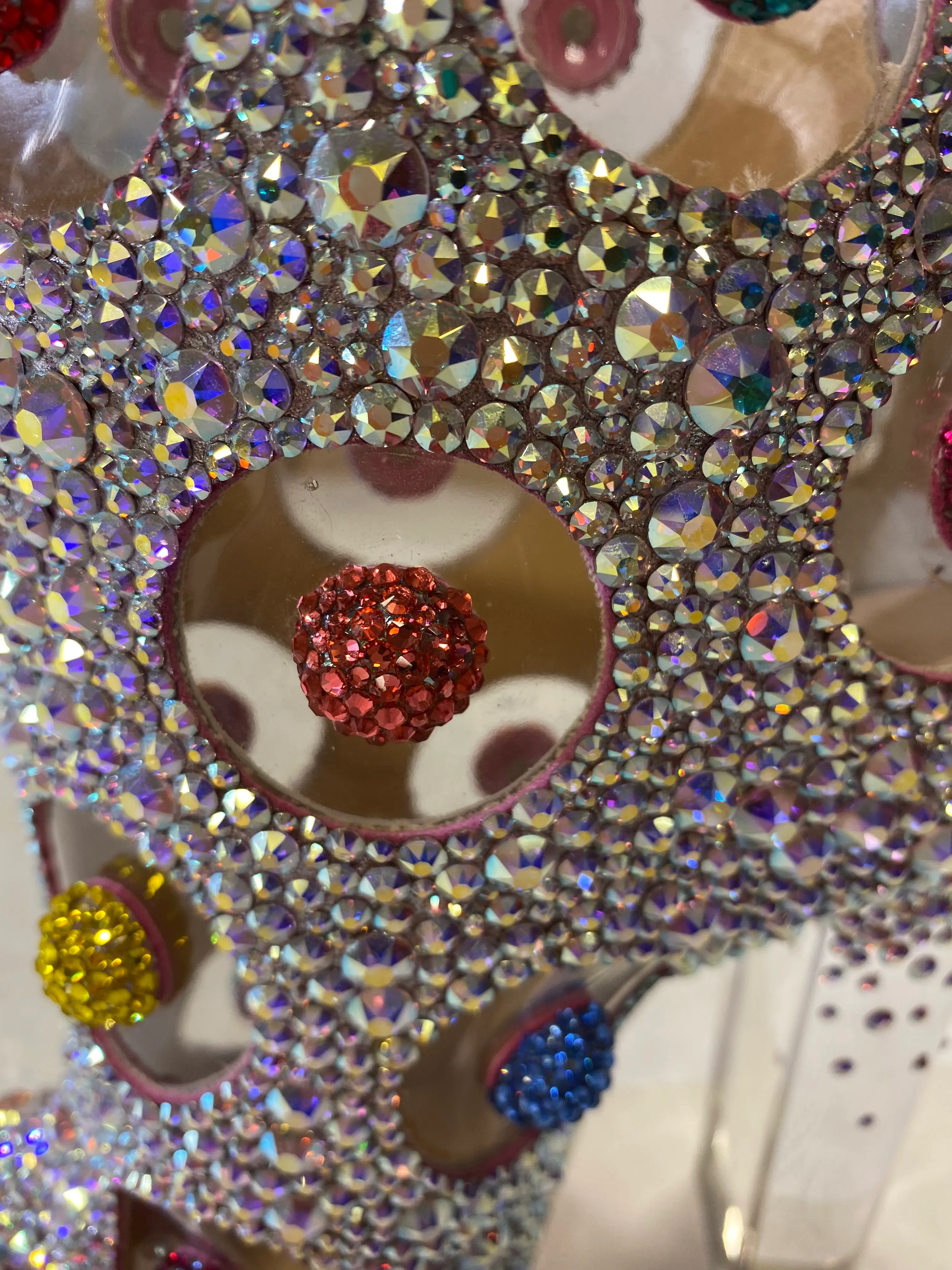 Gros plan sur une décoration ornée de nombreux cristaux brillants multicolores, avec des accents rouges, jaunes et bleus.