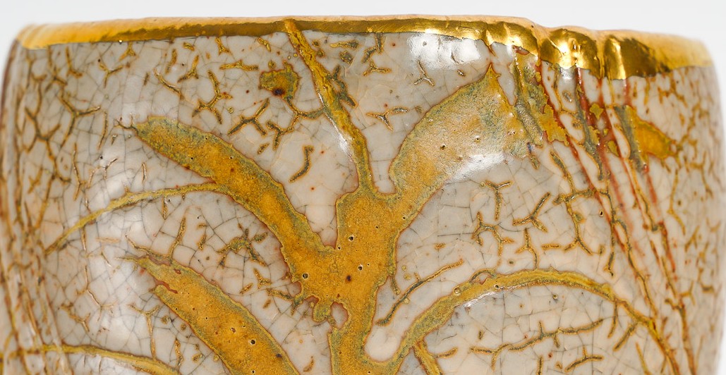 Gros plan d’un bol en céramique avec des fissures dorées décoratives selon la technique du kintsugi.