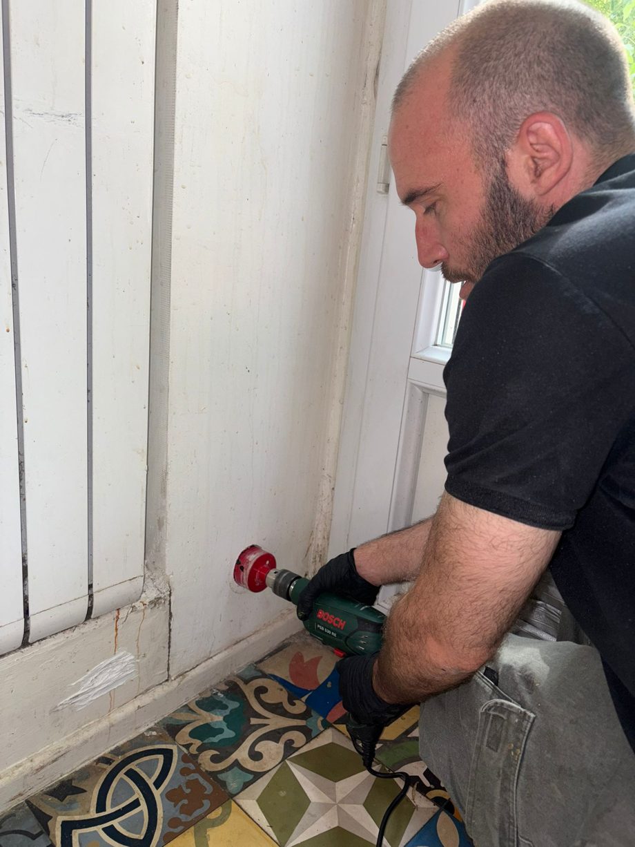 Technicien perçant un coffrage de câbles à la scie-cloche dans un appartement ancien du 3e arrondissement