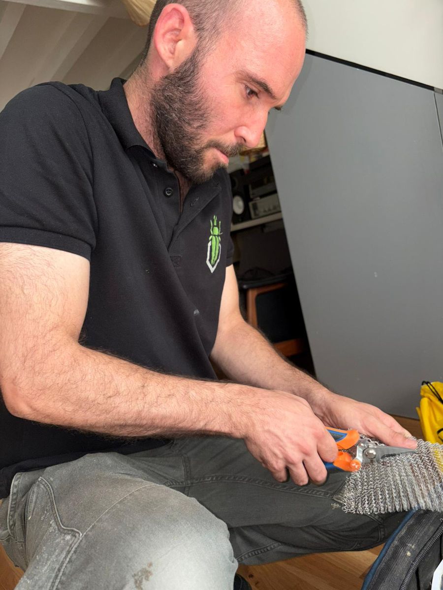 Technicien SafeHome3D découpant une maille en acier inoxydable à la cisaille pour obturer un point d'intrusion de rongeurs à Paris 5e