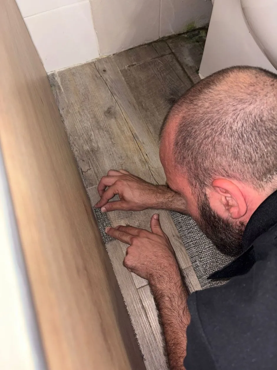 Technicien SafeHome3D insérant une maille de fer découpée sur mesure dans le jour sous la baignoire, Paris 6e