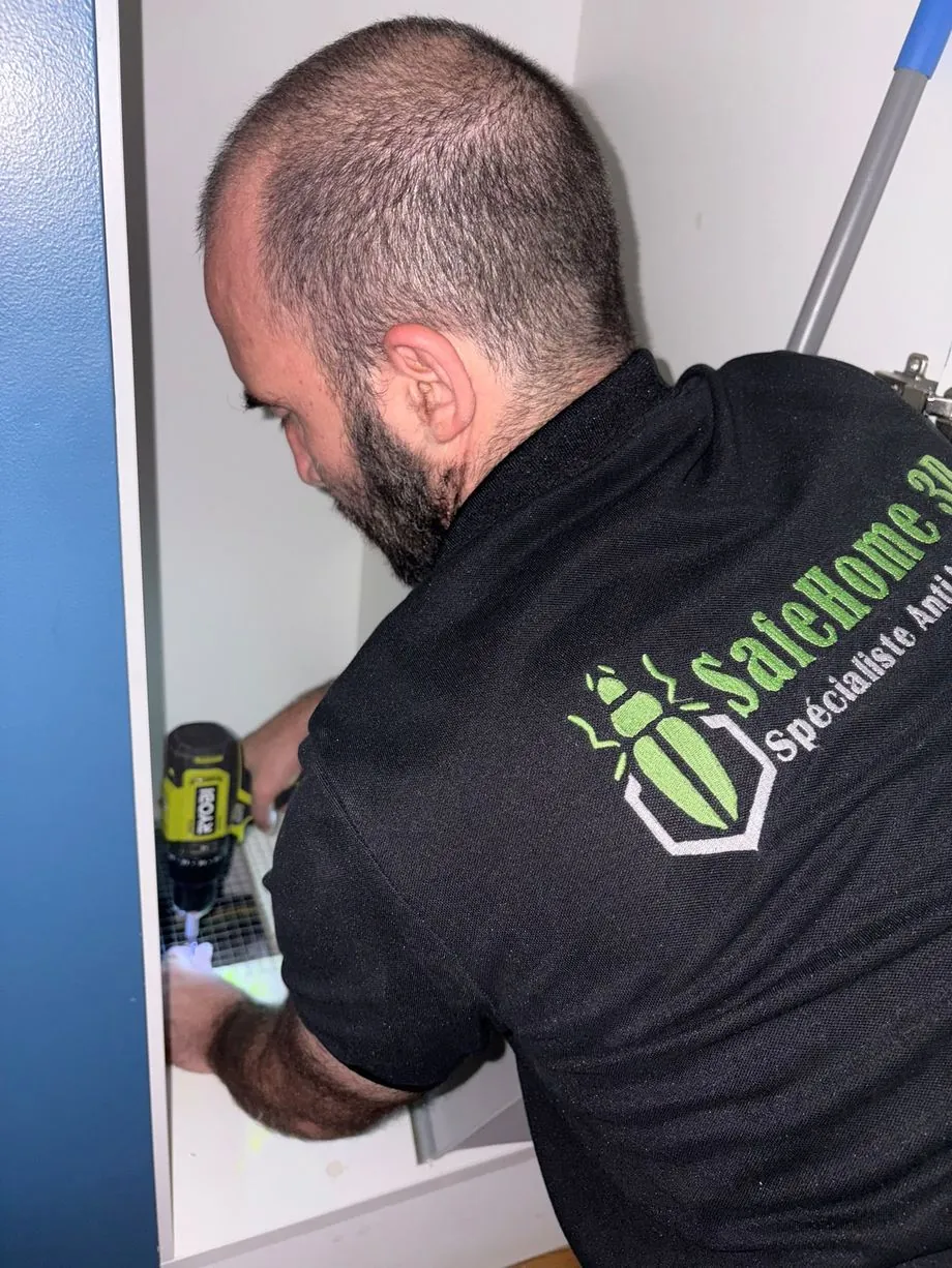 Technicien SafeHome3D vissant un grillage en acier inoxydable découpé sur mesure sur le point d'intrusion, dératisation Paris 5e