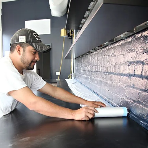 Installer unrolling Easy Mask Tape & Drape masking film along a countertop