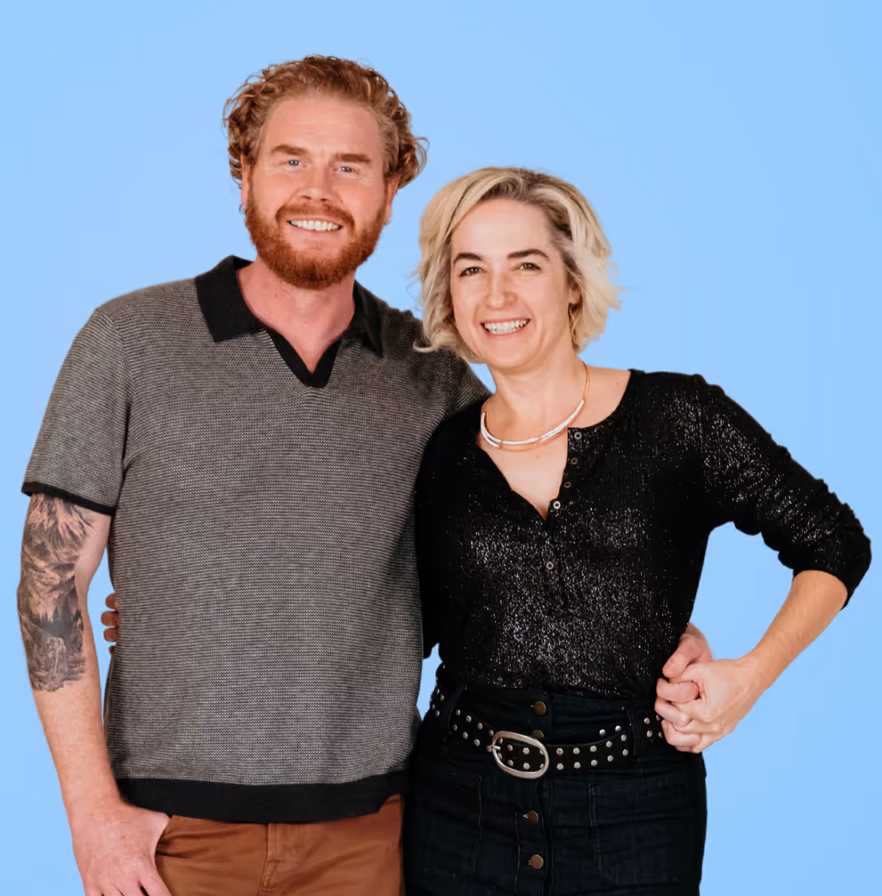 Doug and Lindsey smiling at camera with blue wall