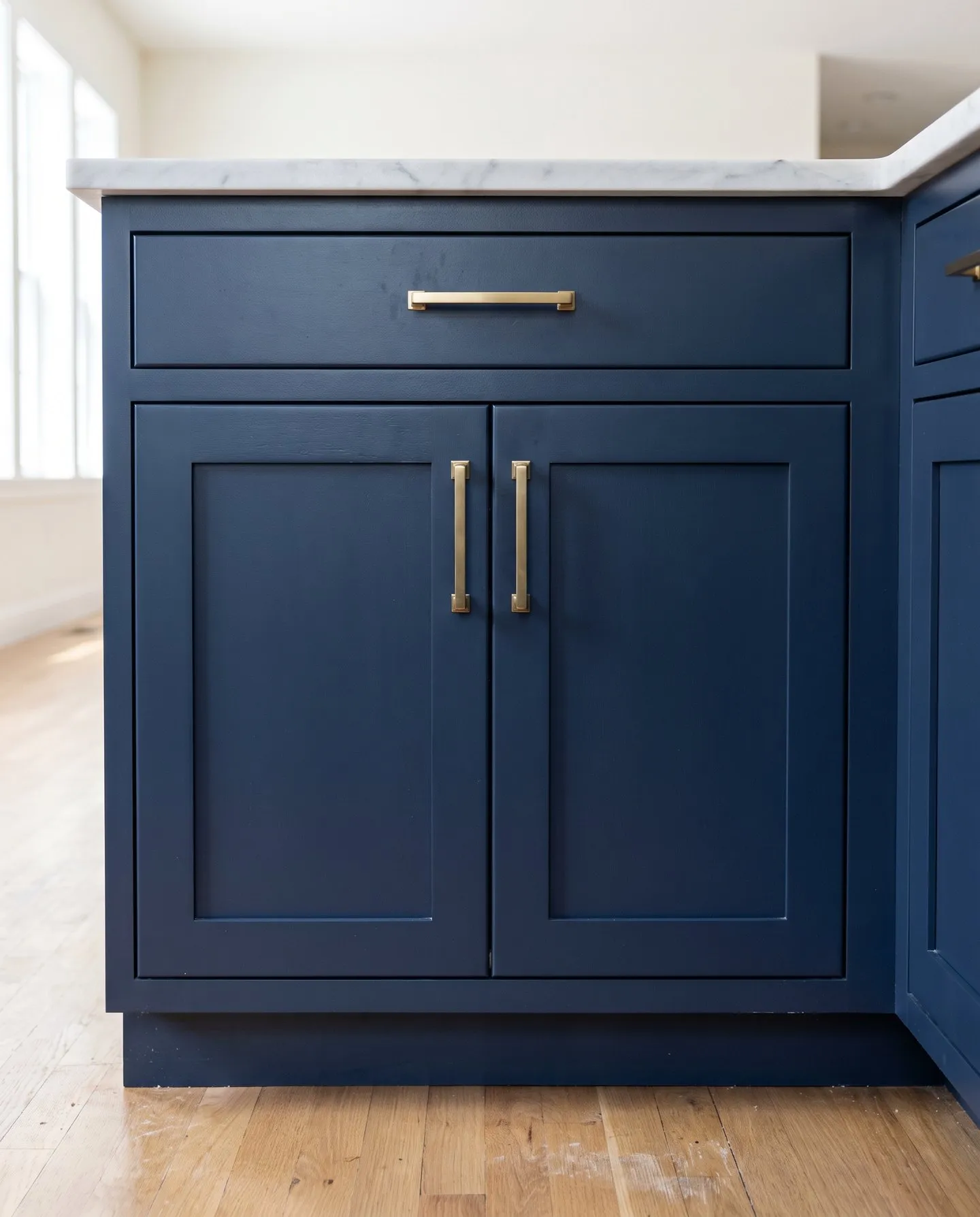 Navy painted shaker base cabinet with a flat center panel in each door and brass pulls