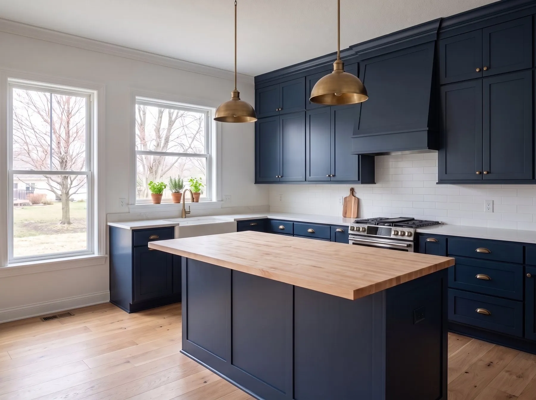 Navy shaker kitchen with brass cup pulls, a wood-topped island and white counters