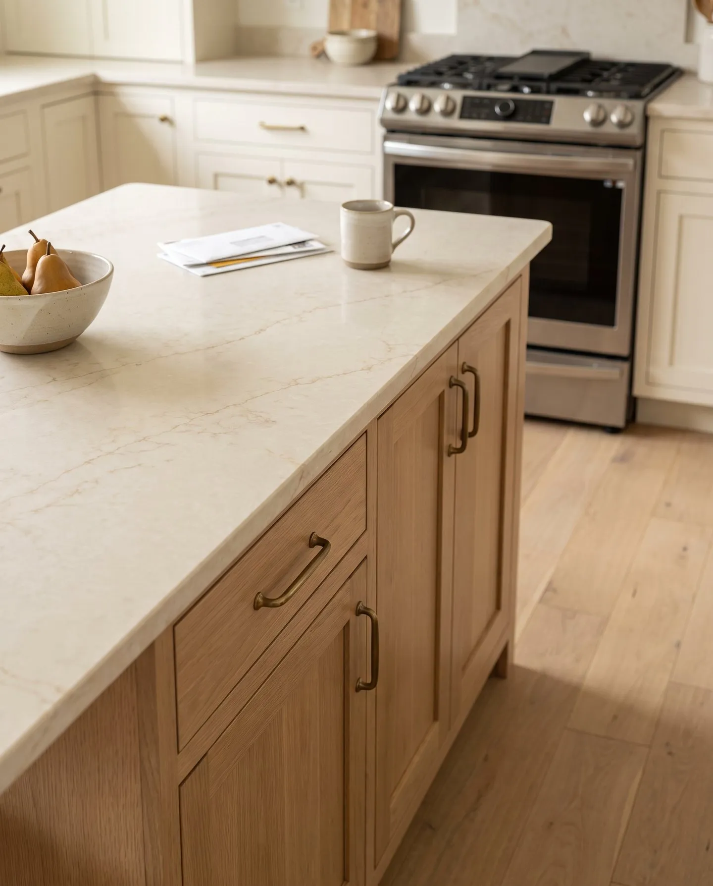 Warm cream island countertop with faint tan veining on a natural oak base