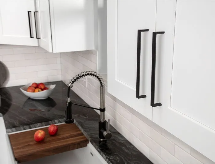Elements matte black squared pulls on white cabinet doors above a dark stone counter