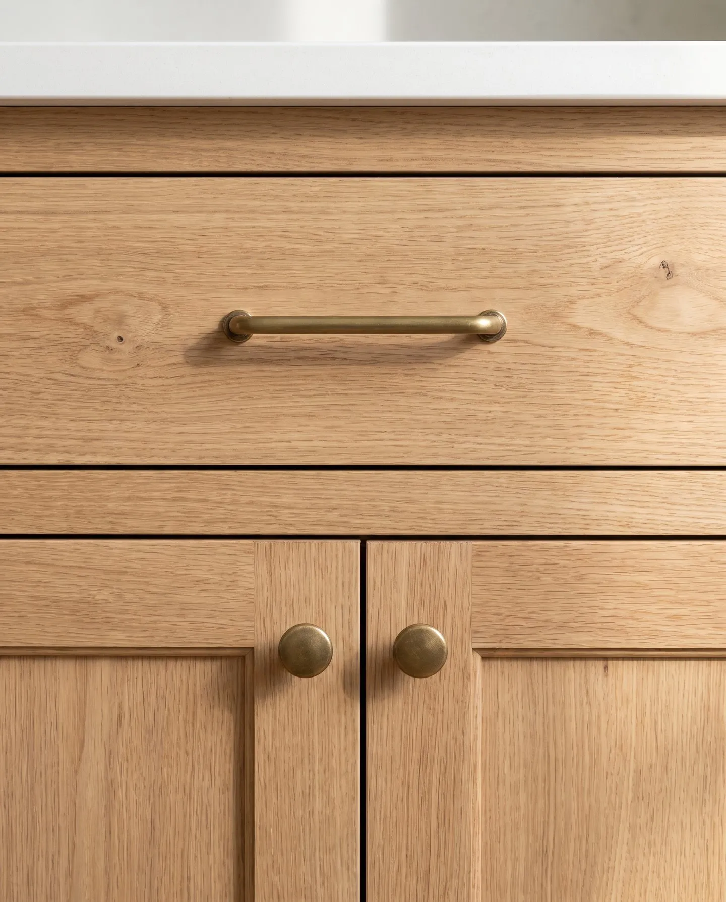 Aged brass bar pull and knobs on natural oak cabinet fronts