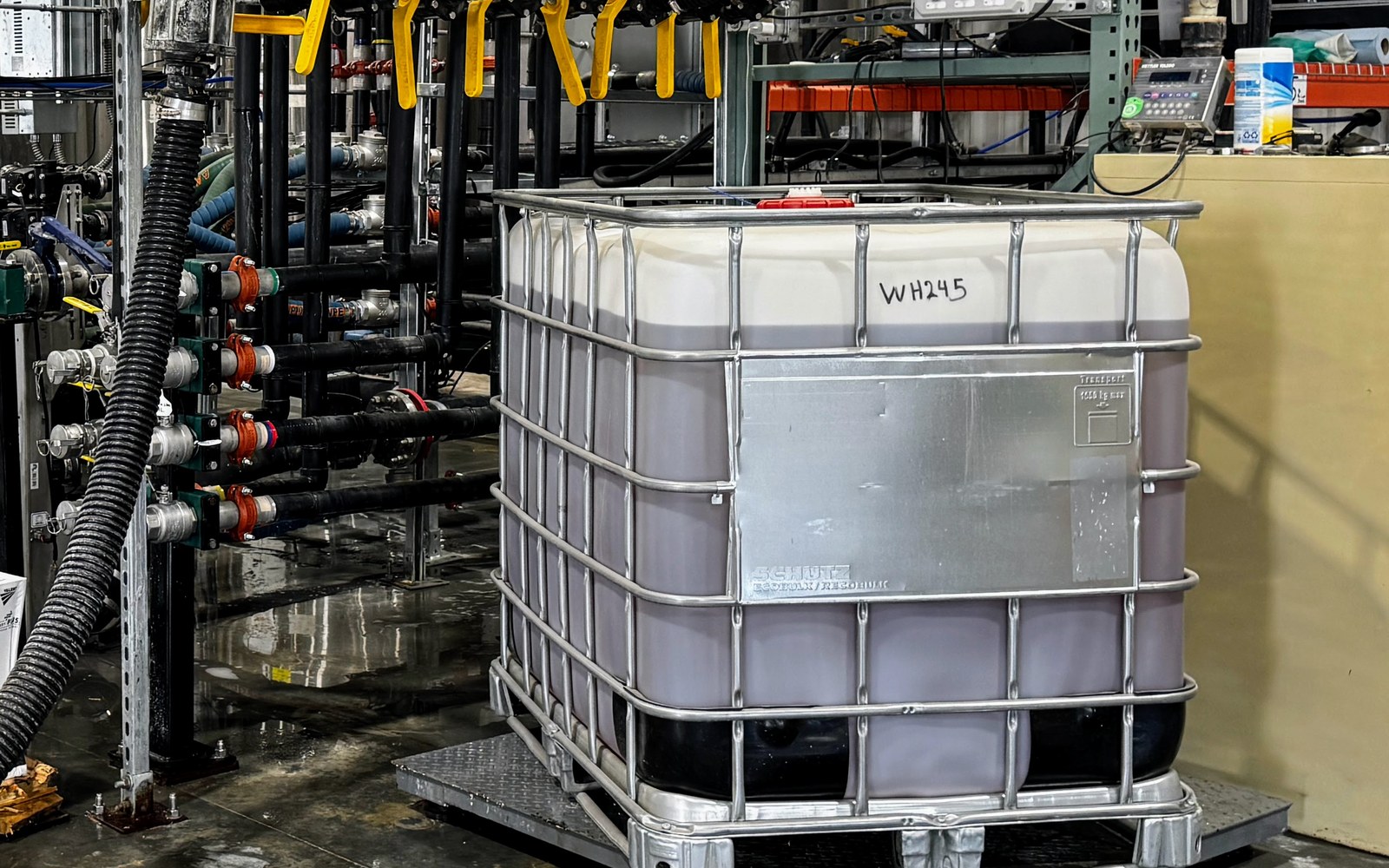 Bulk repack station: a tote on a platform scale next to a Mixmate Flow manifold