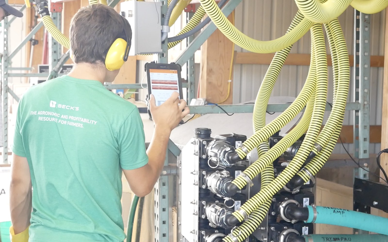 Operator running Mixmate on a tablet beside a closed valve stack, no contact with product