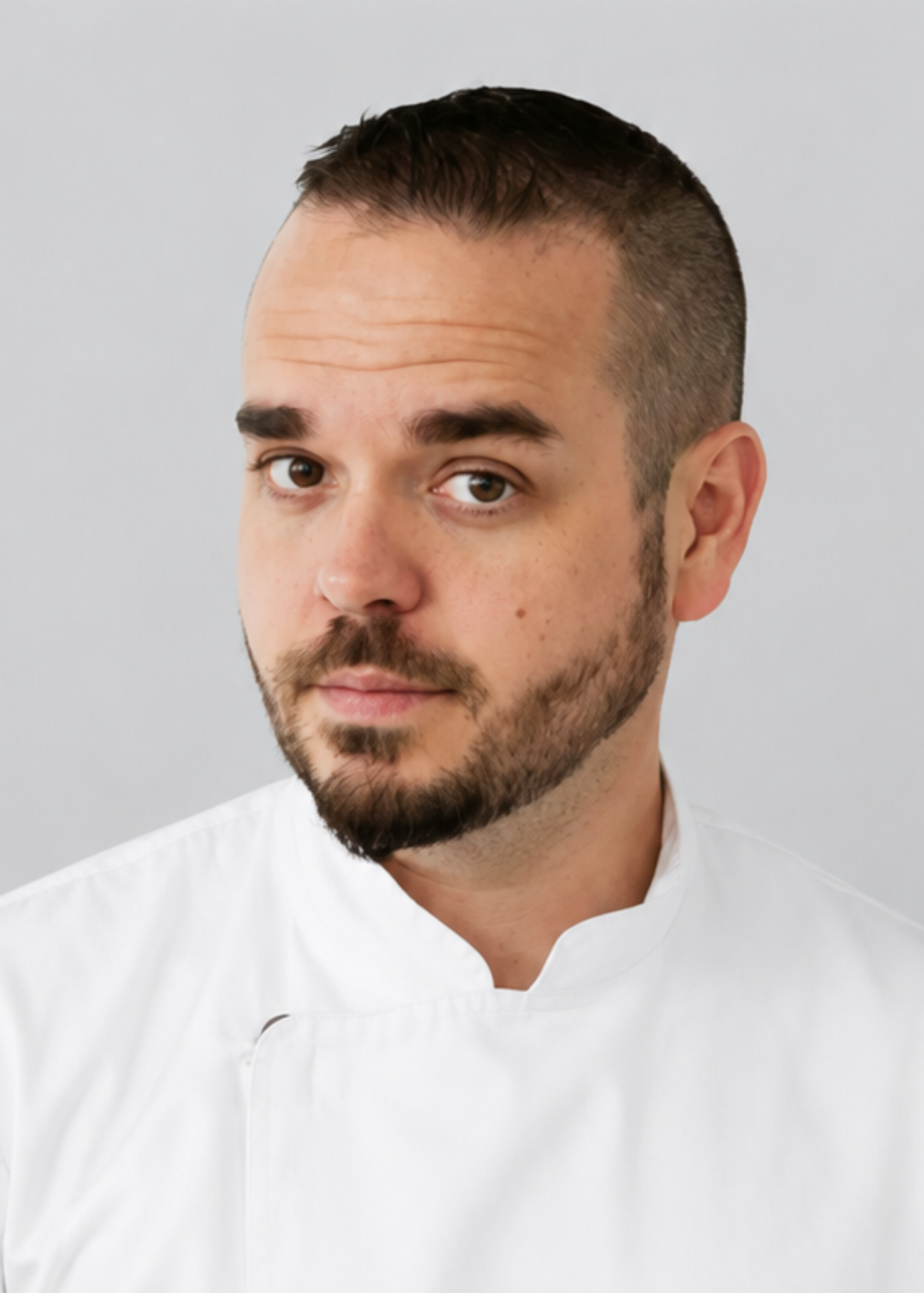 A professional studio headshot of Executive Chef Rick Bower wearing a white chef's coat, leading the wedding catering and event culinary design team at Heritage Social in Douglas, Michigan.