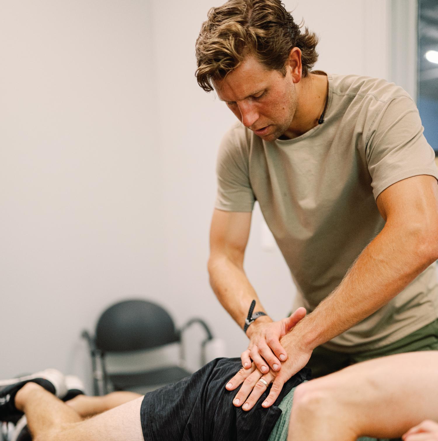 A therapist performing manual therapy or chiropractic treatment on a person's lower back.