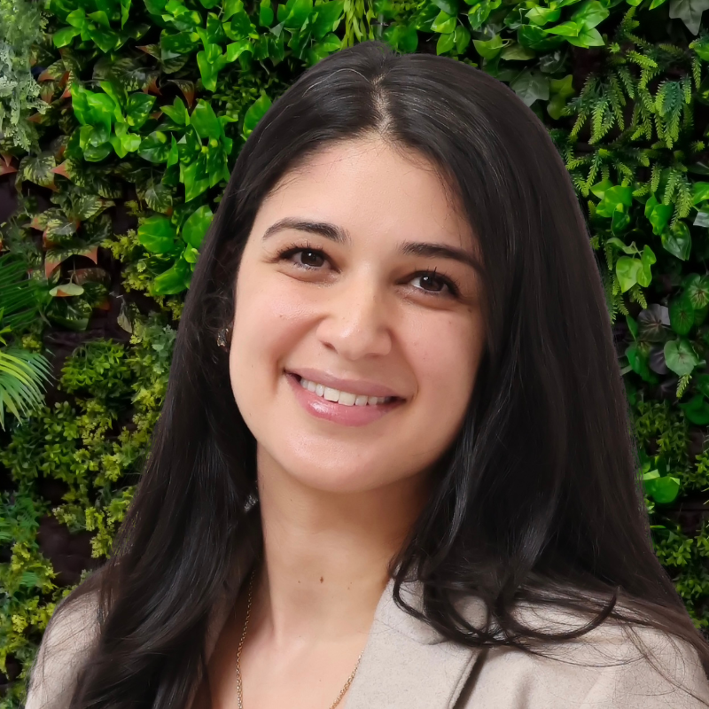 Smiling man with glasses, brown hair, and a beard wearing a purple shirt and black jacket.
