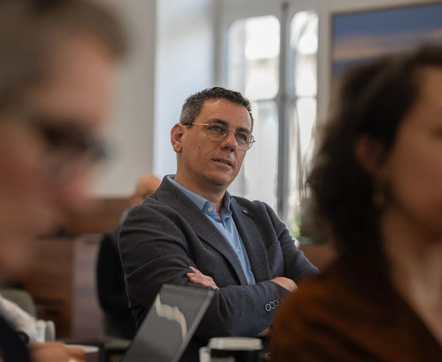 A man listening with arms crossed during a business meeting