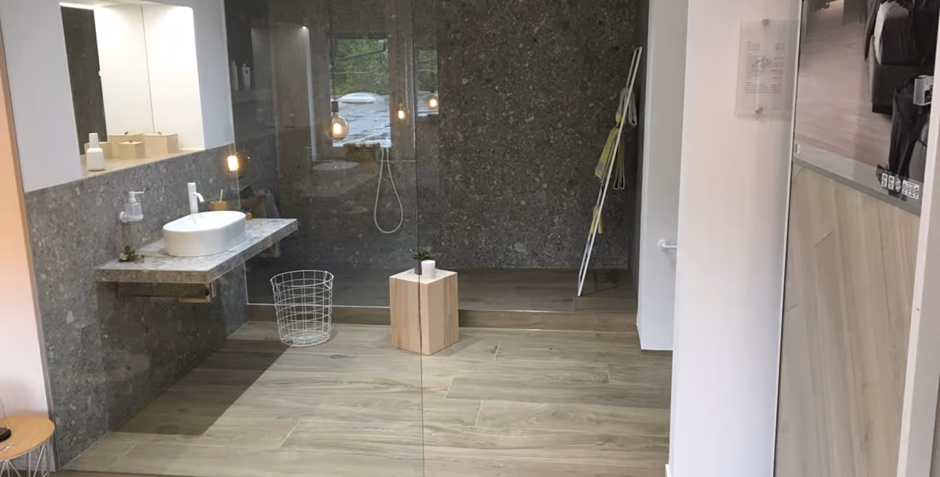 Modernes Badezimmer mit wandhängendem Waschbecken, Glasdusche, Holzfliesenboden und minimalistischem Design.