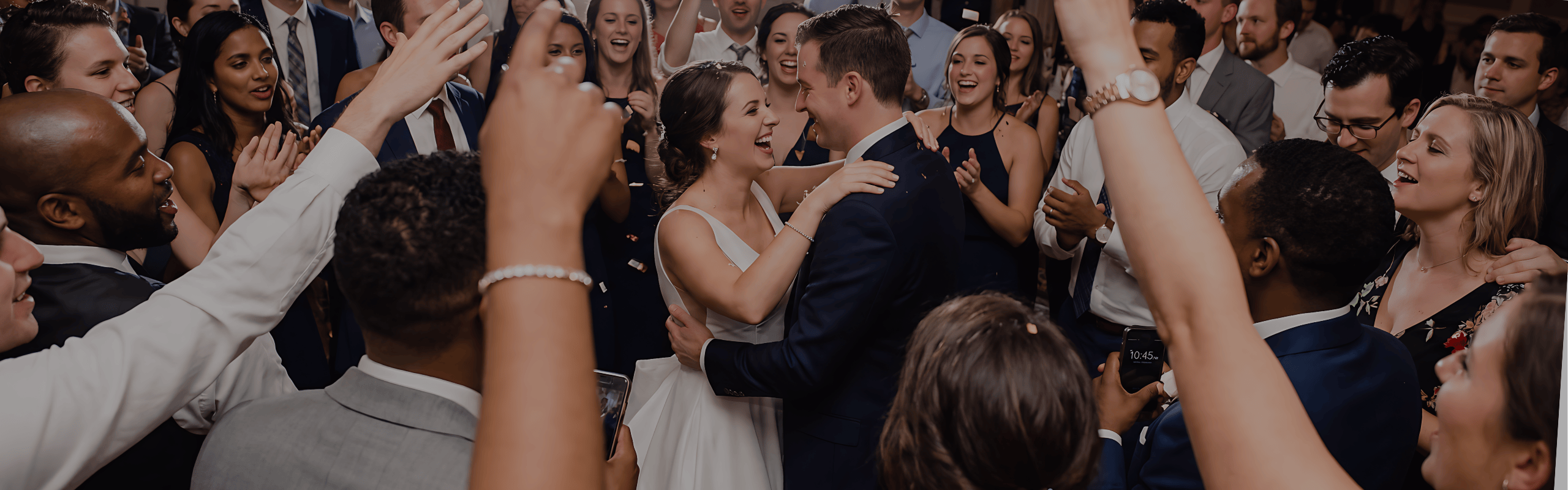 Bride and groom laughing and dancing surrounded by joyful wedding guests cheering and clapping.