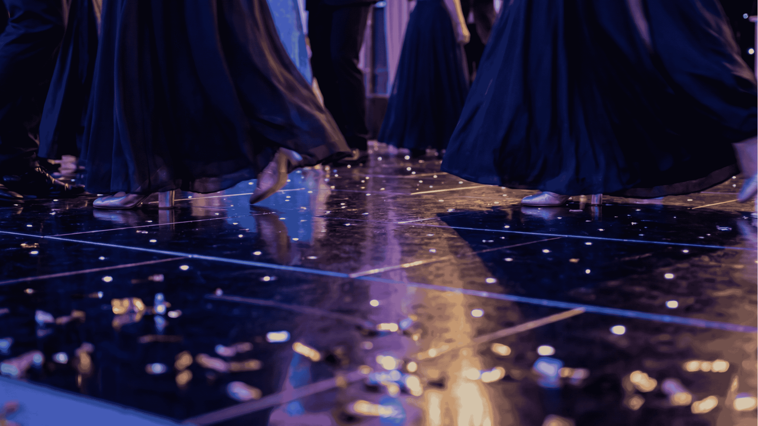 Close-up of dancers’ feet in elegant dresses and shoes moving on a shiny confetti-covered floor.