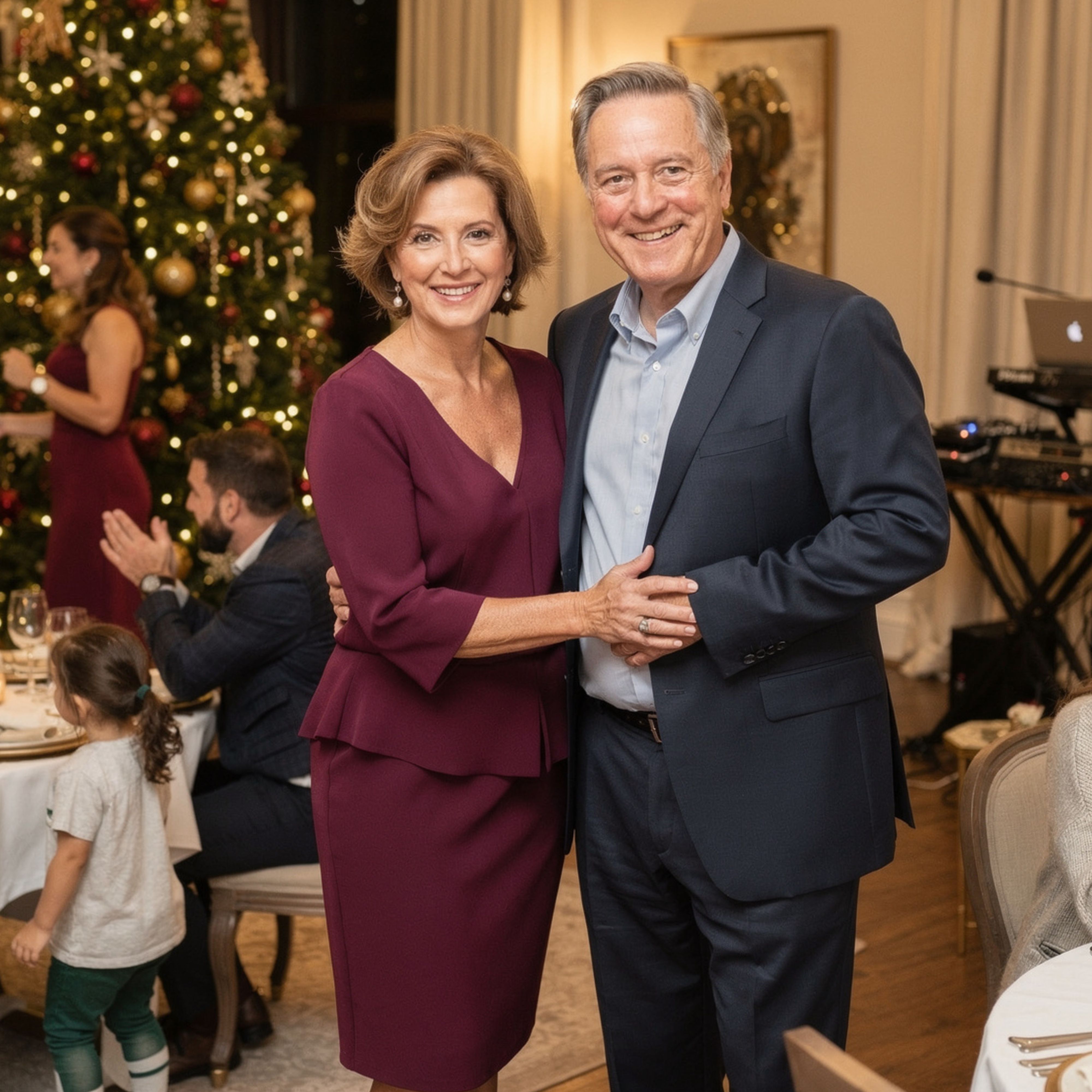 Smiling couple dressed formally posing together at a festive indoor event with a decorated Christmas tree.