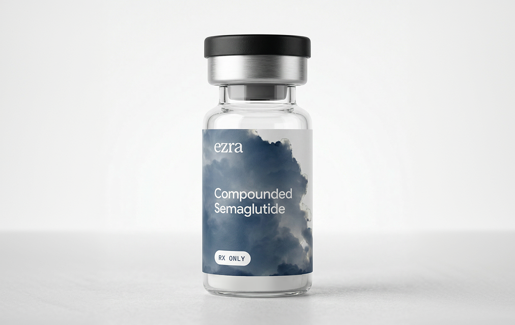 Clear vial with black cap labeled 'ezra Compounded Semaglutide RX ONLY' with a cloudy sky background on the label.