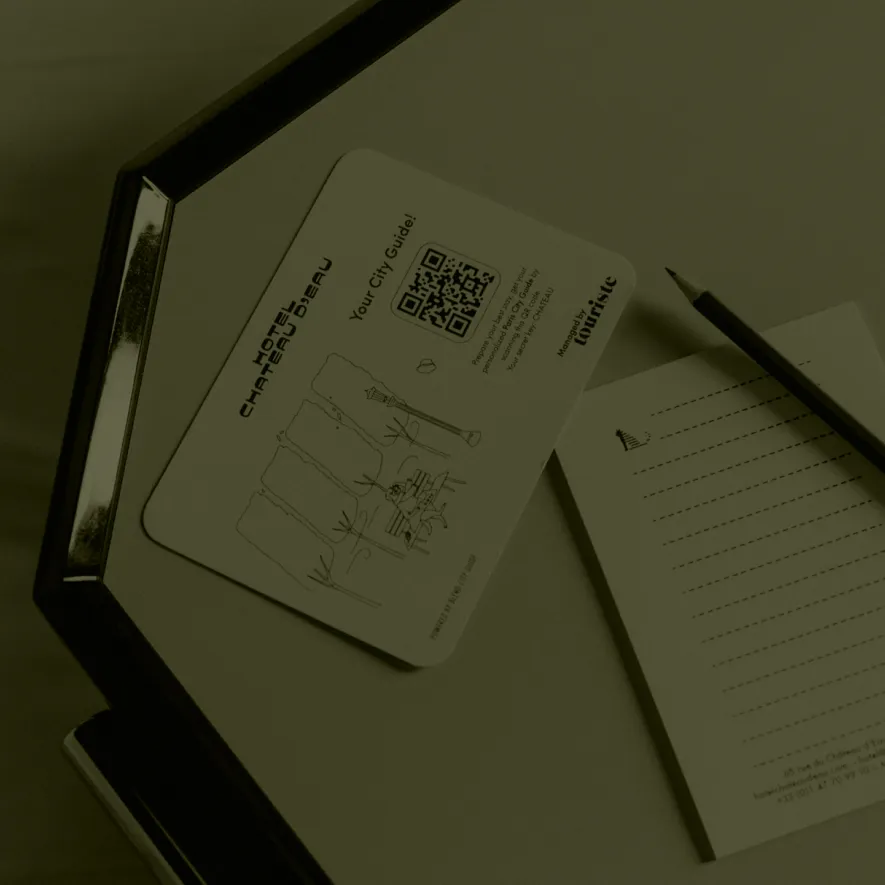 Carte de guide de la ville de l'Hôtel Château-Breau avec un QR code sur une table à côté d'un carnet et d'un crayon.