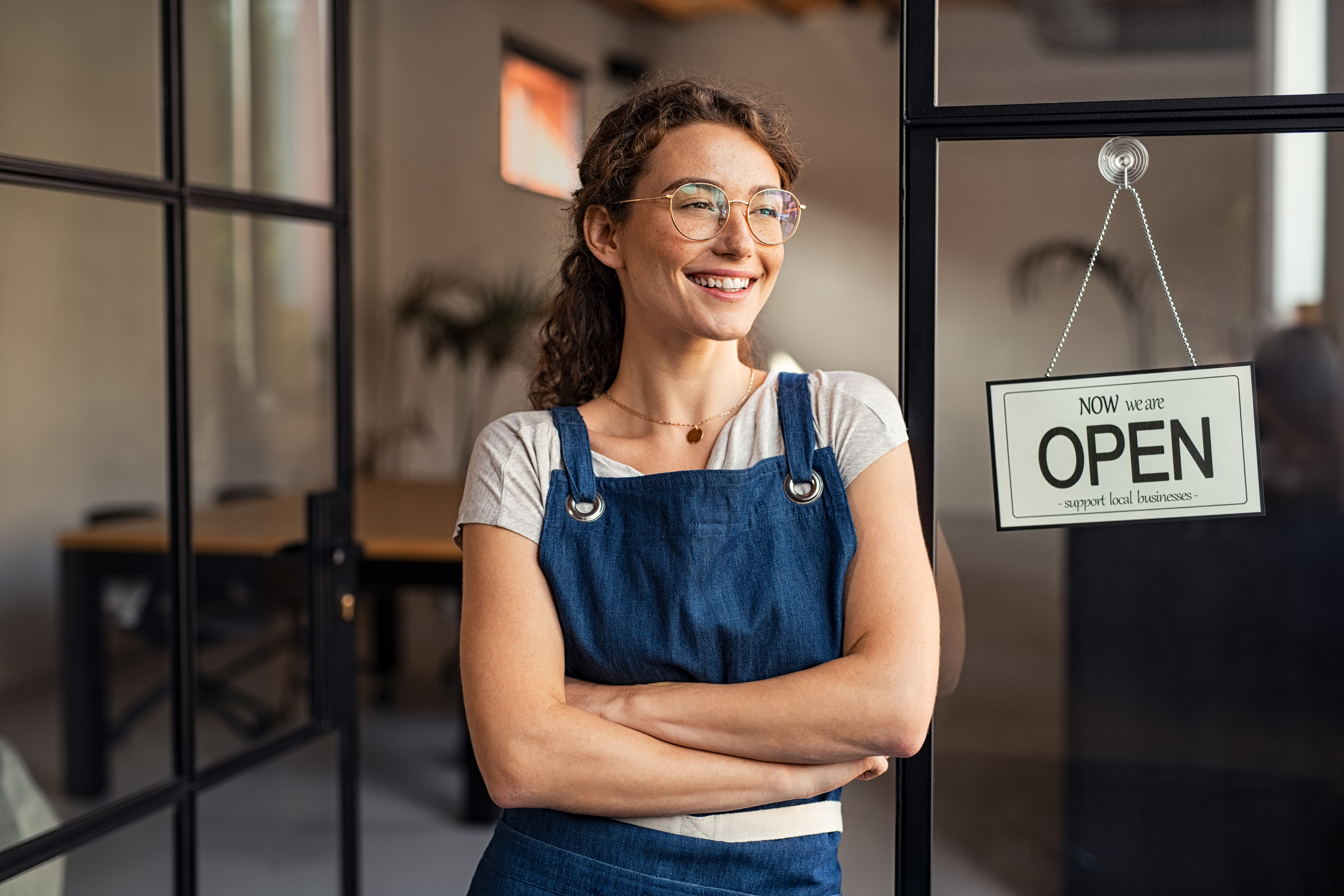 business owner smiling in front of open store sign
