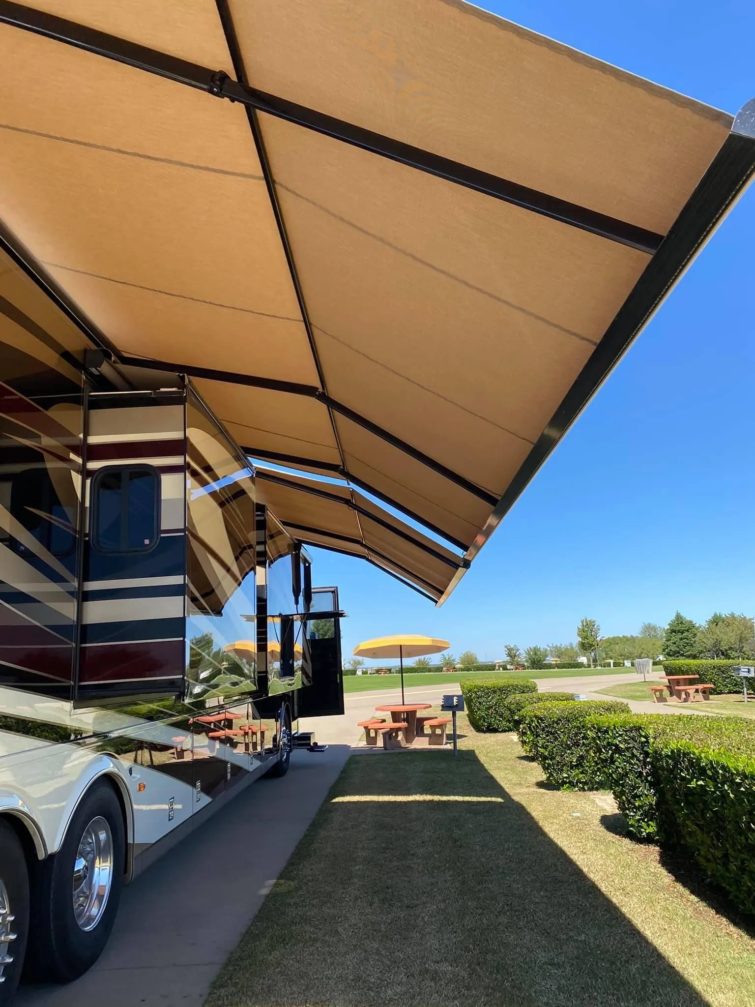 Luxury motorhome parked under an awning at a manicured RV resort site
