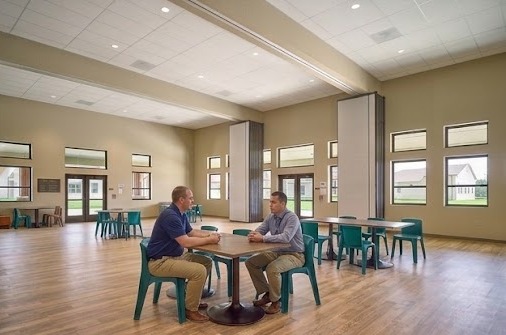 Two staff members talk at a table in a bright, open common room at the Residential Center