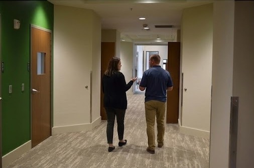 A Shift Supervisor walks a lodge hallway with a colleague, checking in during a shift