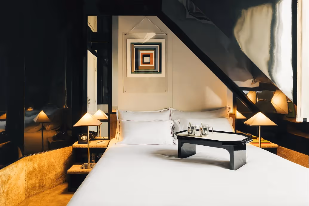 Suite sous combles au design graphique avec plateau de service sur lit, Hôtel Château d’Eau 4 étoiles, Paris 10e.