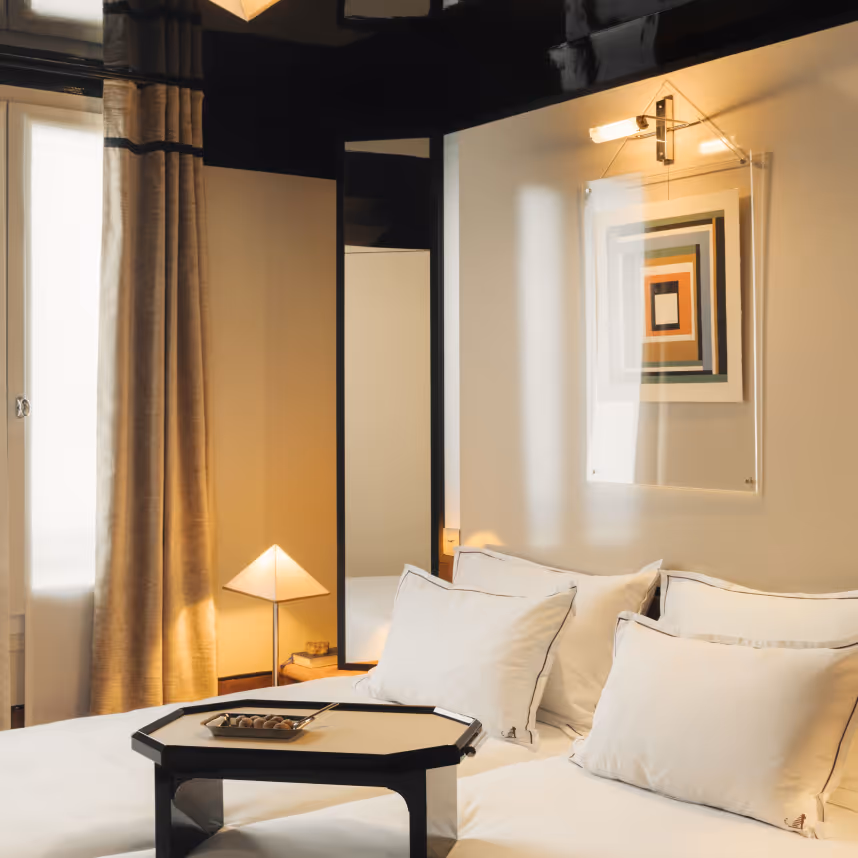 Suite élégante, lit blanc, plateau petit-déjeuner et cadre art, Hôtel Château d’Eau quatre étoiles, Paris.