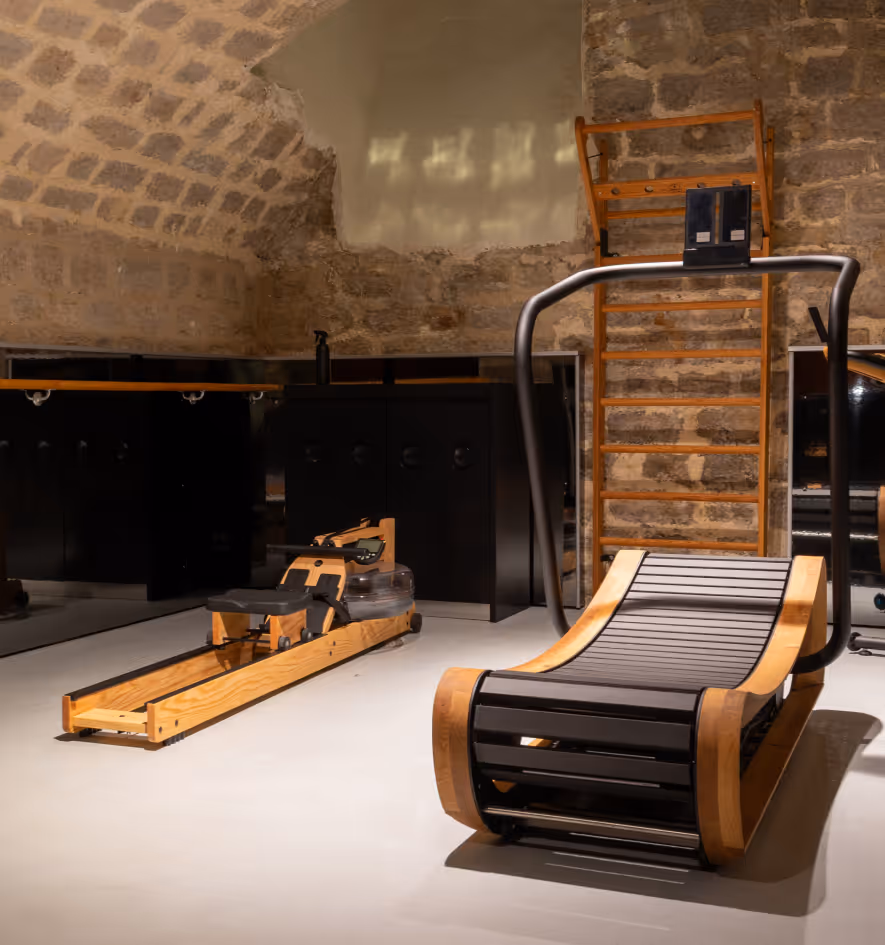 Fitness area with high-end wooden equipment, including a rower and a treadmill, at Hotel Château d’Eau, a 4-star boutique hotel in Paris.