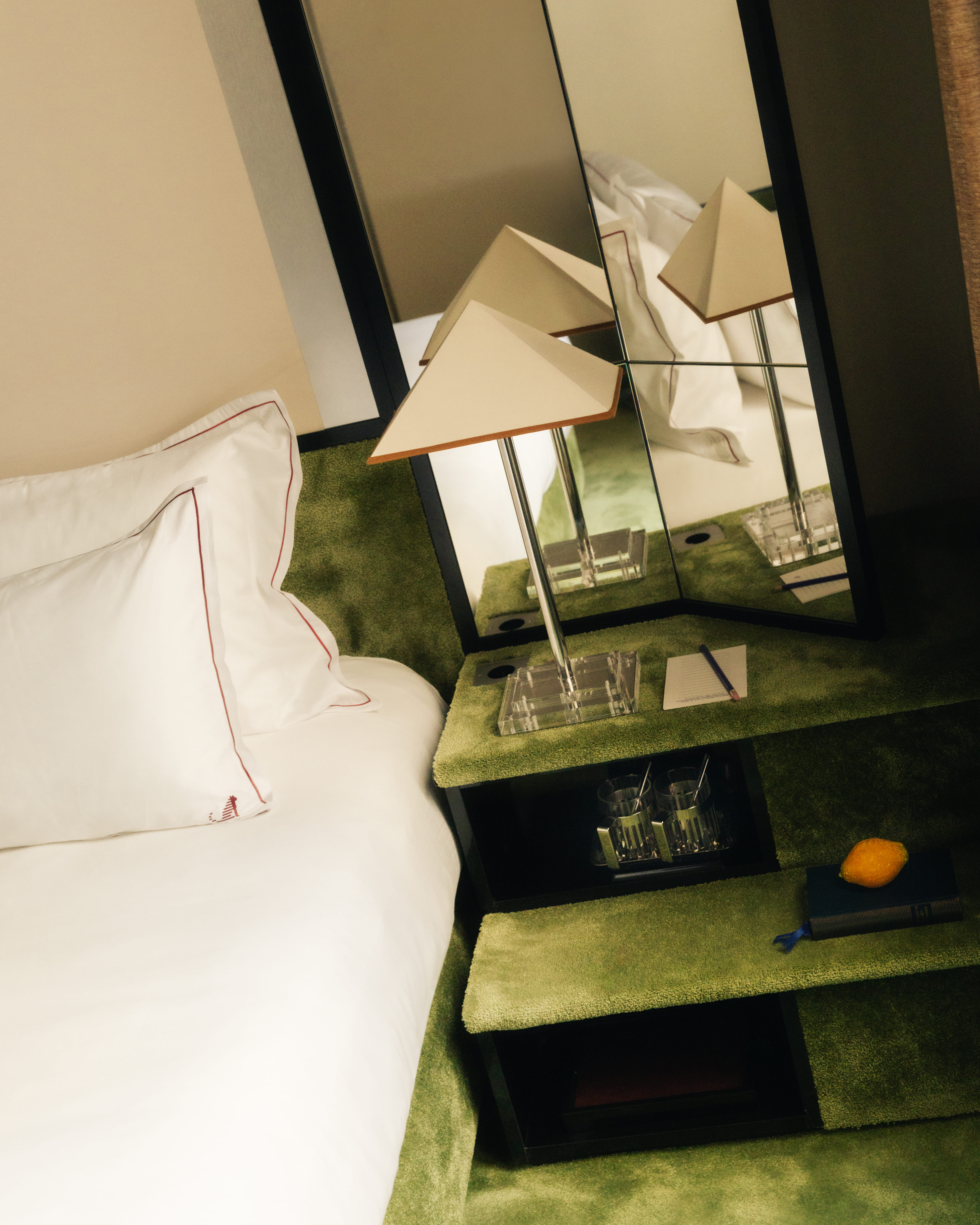 Textured green bedside table with a pyramid lamp and mirror, Château d’Eau 4-star Hotel, Paris.