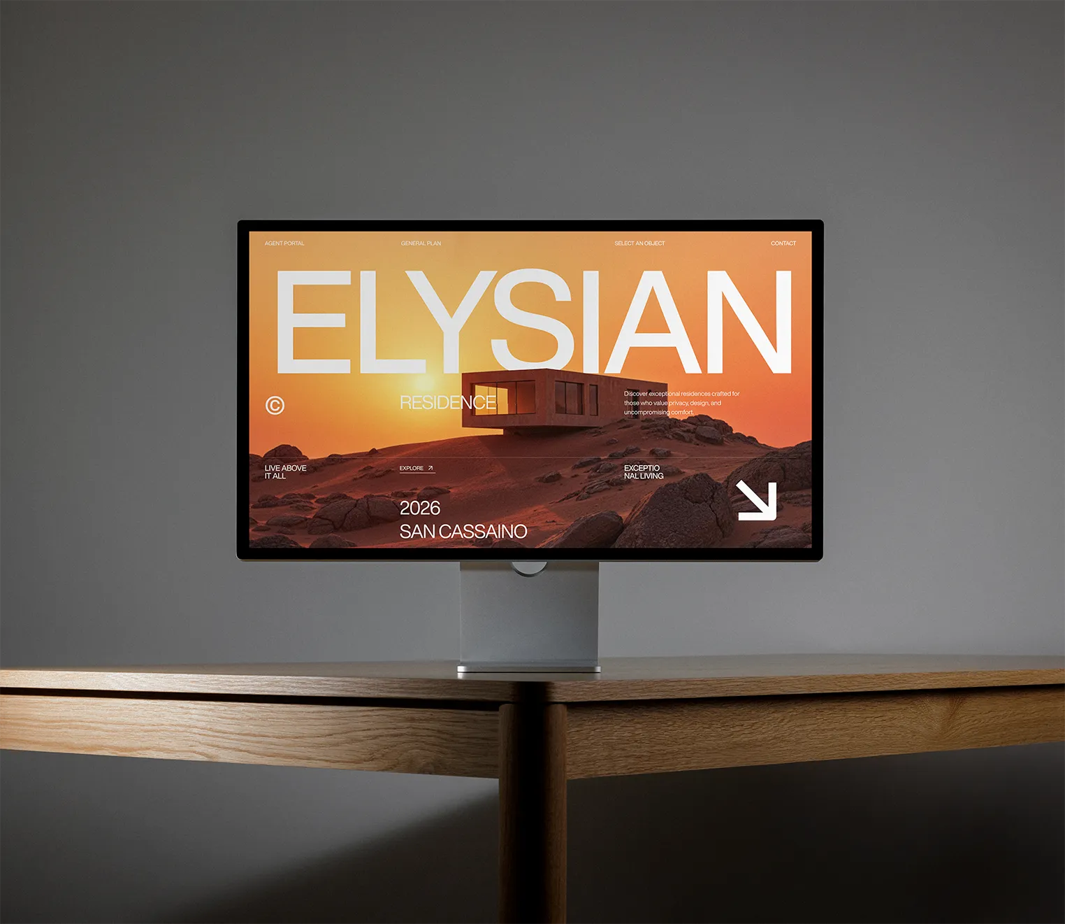 A modern desktop monitor on a wooden table displaying a real estate advertisement with the text ELYSIAN RESIDENCE and an image of a house on a rocky landscape at sunset.