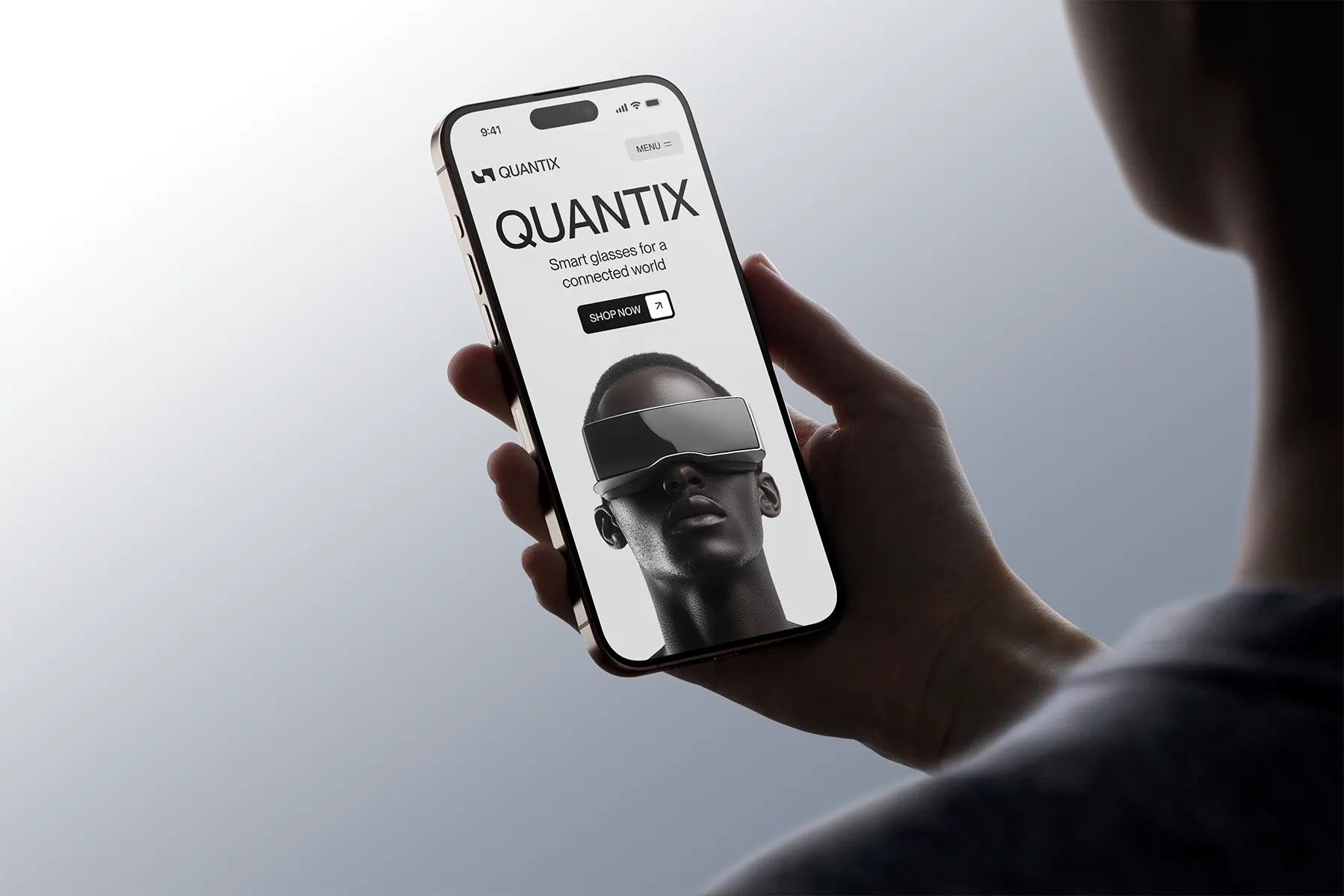 Person holding a smartphone displaying the Quantix website with an advertisement for smart glasses featuring a model wearing large futuristic glasses.