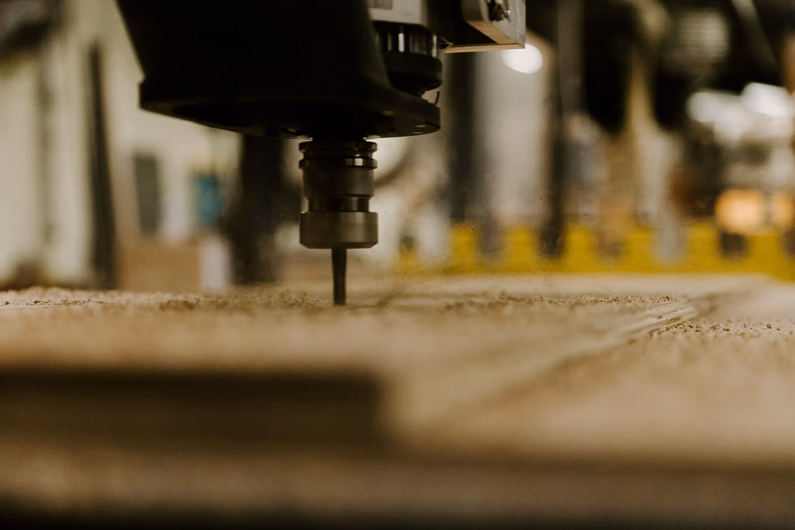 Close-up of a CNC machine cutting a wooden board in a workshop.