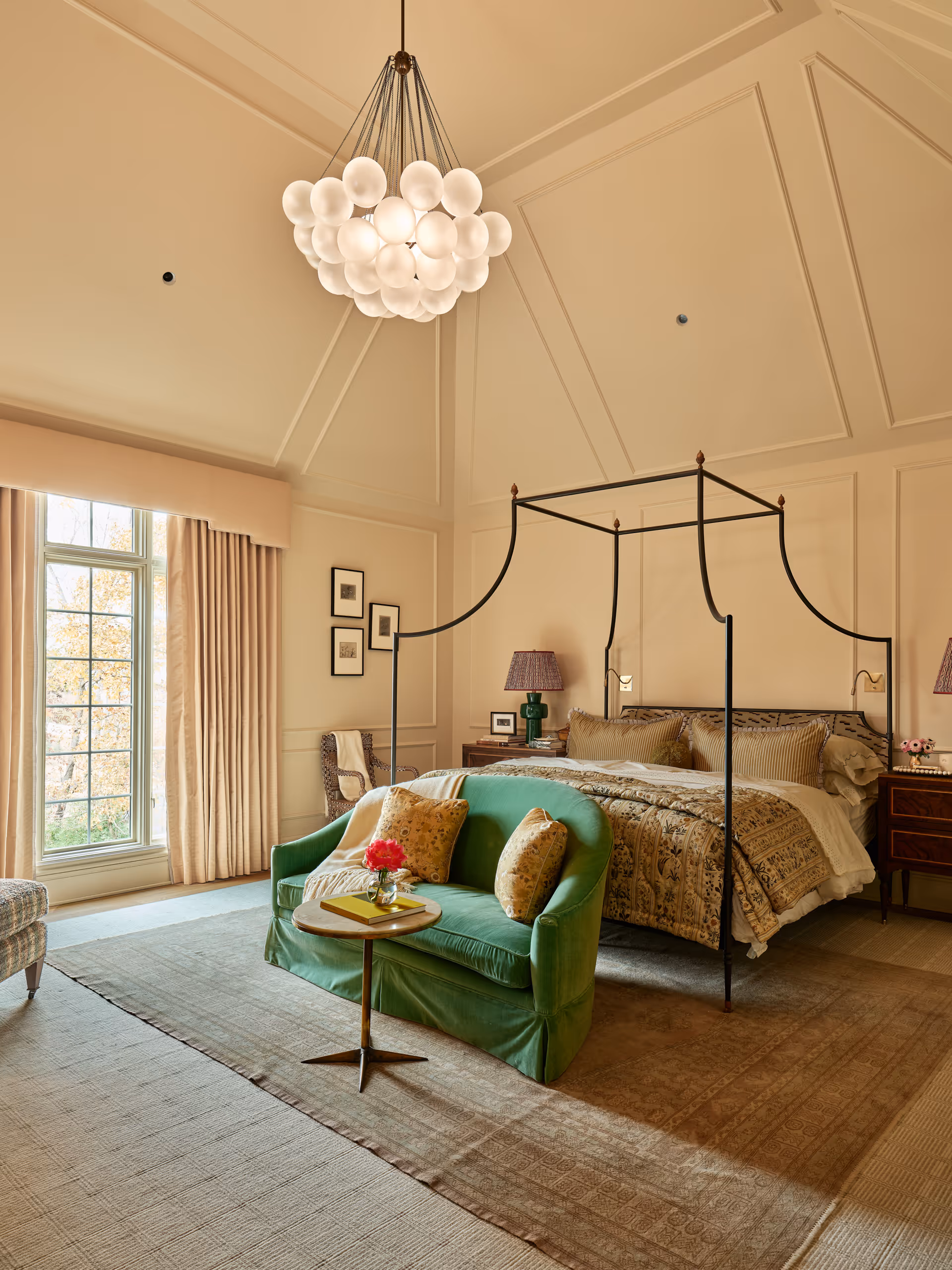 Spacious bedroom with a metal canopy bed, patterned bedding, green loveseat with pillows