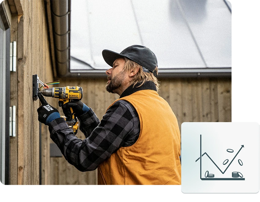 Man using a drill to install an electrical outlet on a wooden wall outside.